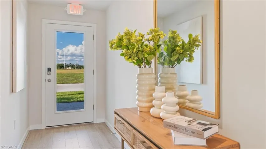 Model home. Doorway with hardwood / wood-style floors and baseboards