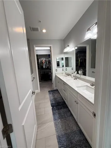 Bathroom featuring a walk in closet, double vanity, recessed lighting, and tile patterned floors