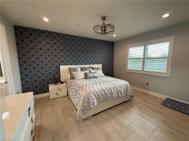 Bedroom with an accent wall, wallpapered walls, wood finish floors, and recessed lighting