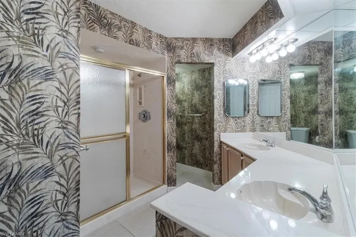 Bathroom featuring vanity, toilet, tile patterned flooring, and a shower with door