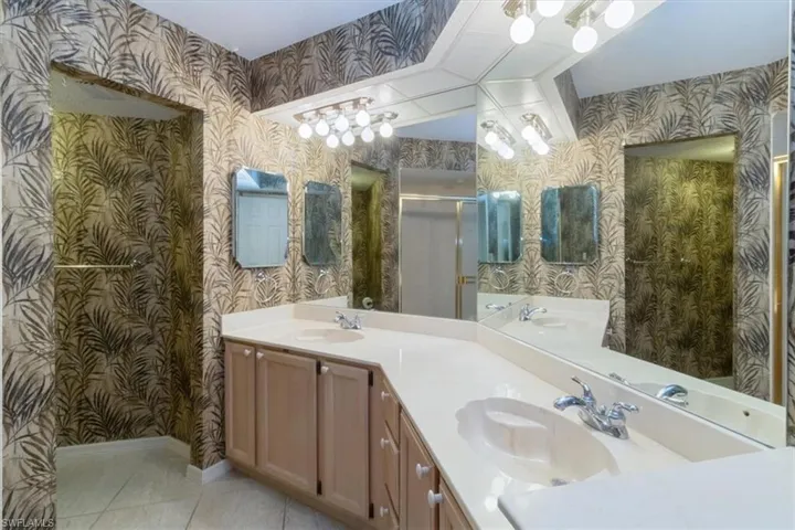 Bathroom featuring tile patterned flooring, vanity, and an enclosed shower