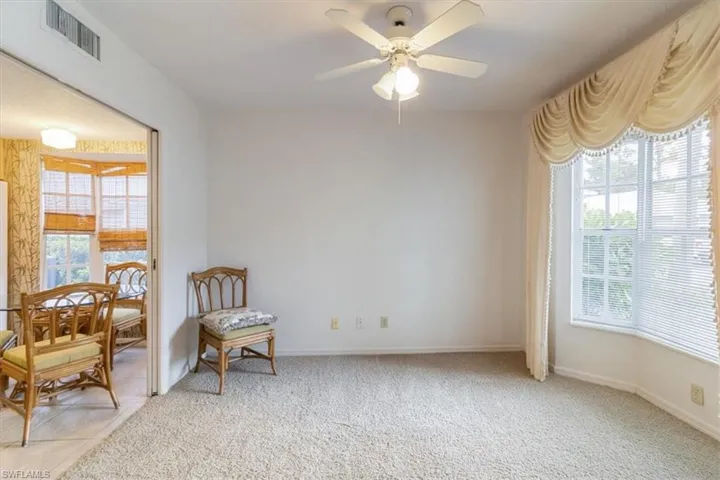 Living area featuring light colored carpet and ceiling fan