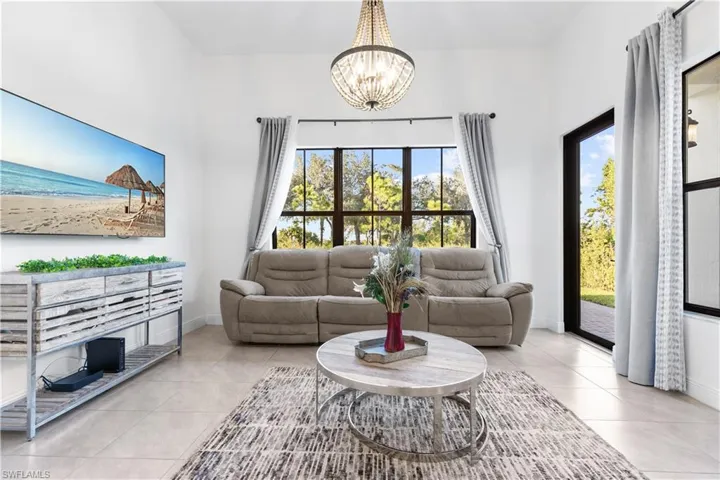 Tiled living room with a healthy amount of sunlight and a chandelier