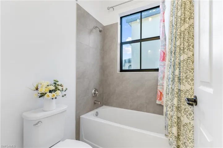 Bathroom with toilet and shower / bath combination with curtain