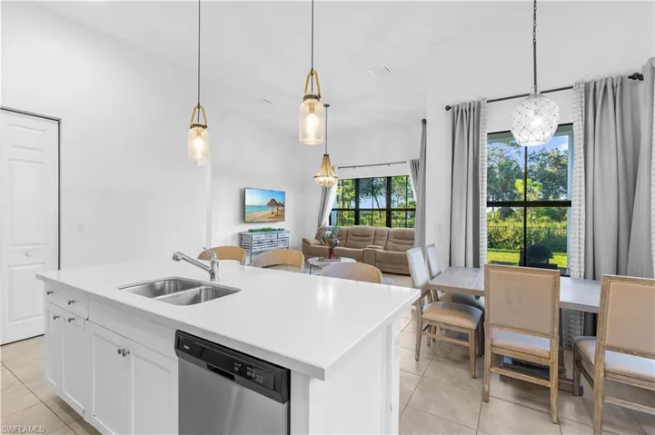 Kitchen featuring sink, plenty of natural light, decorative light fixtures, stainless steel dishwasher, and a kitchen island with sink