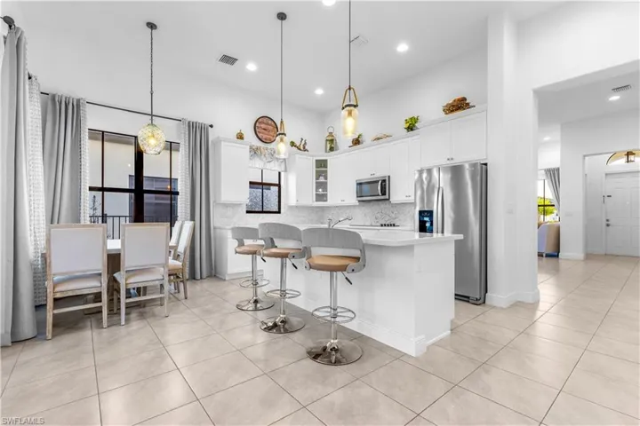 Kitchen with appliances with stainless steel finishes, white cabinetry, pendant lighting, and a kitchen island