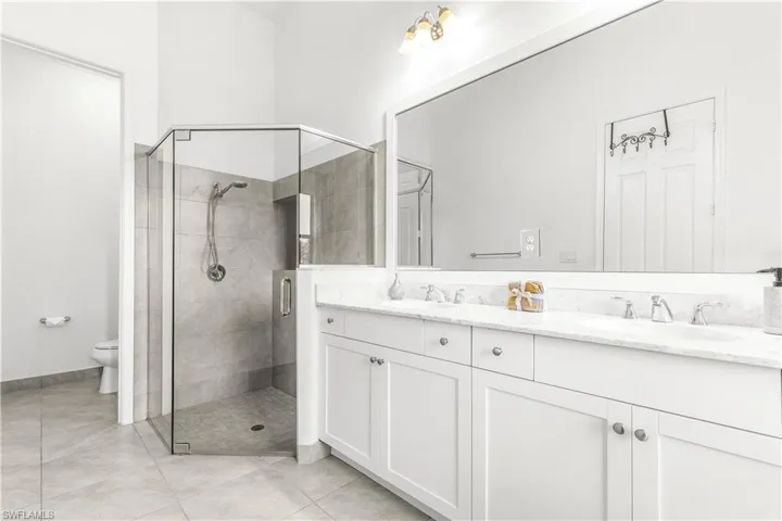 Bathroom featuring vanity, a shower with shower door, toilet, and tile patterned floors