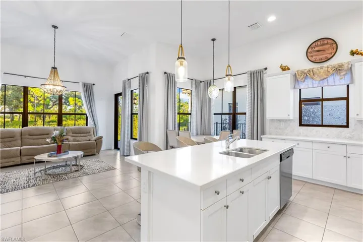 Kitchen with plenty of natural light, a chandelier, sink, and an island with sink