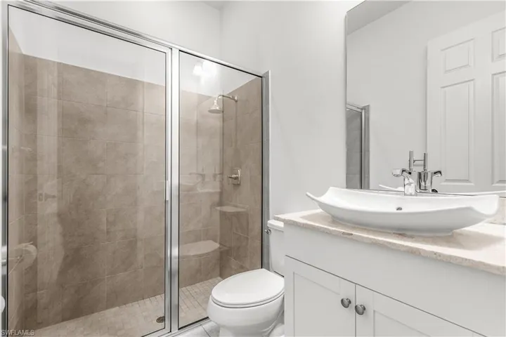Bathroom with vanity, a shower with shower door, and toilet