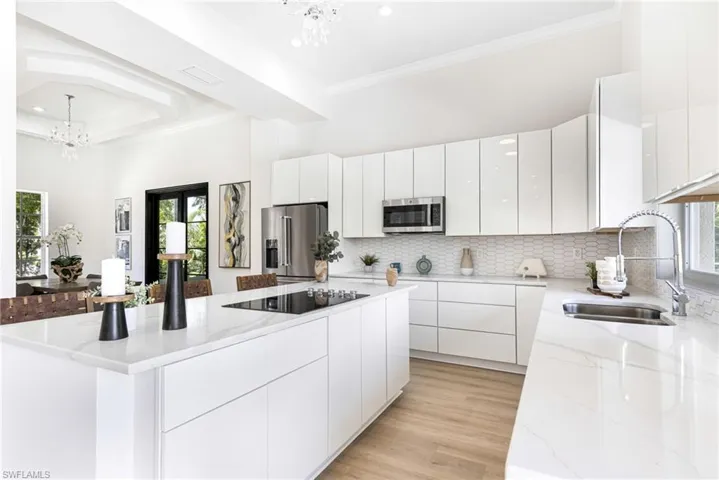 Kitchen with sink, appliances with stainless steel finishes, a chandelier, and a wealth of natural light