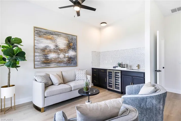 Master bedroom living room with sink, ceiling fan, wine cooler, and light hardwood / wood-style floors