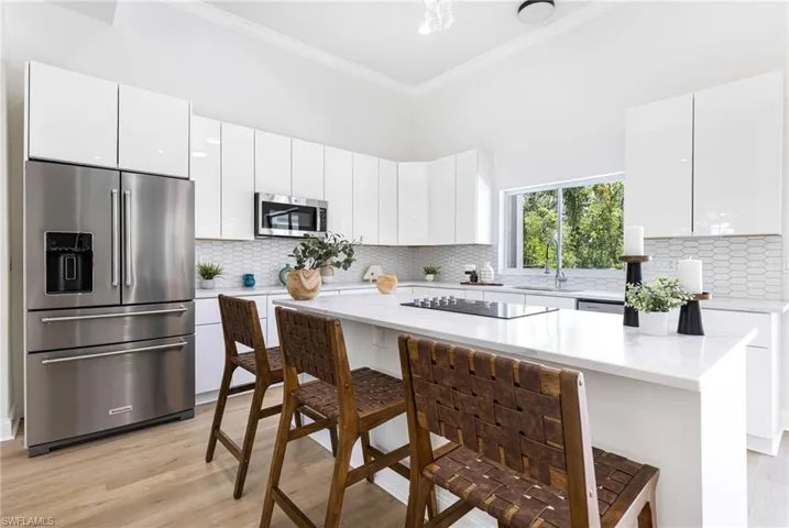Kitchen with tasteful backsplash, stainless steel appliances, sink, light hardwood / wood-style flooring, and a kitchen breakfast bar