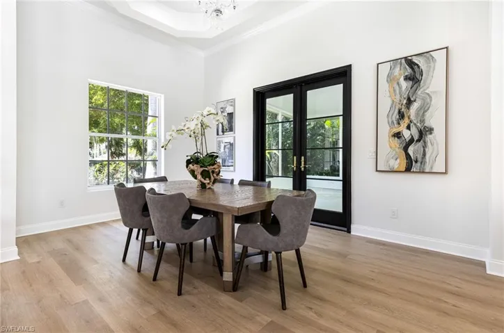 Dining room with light hardwood / wood-style floors, an inviting chandelier, french doors, and a open volume ceilings