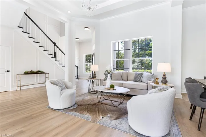 Living room with a high ceiling, crown molding, and light hardwood / wood-style flooring