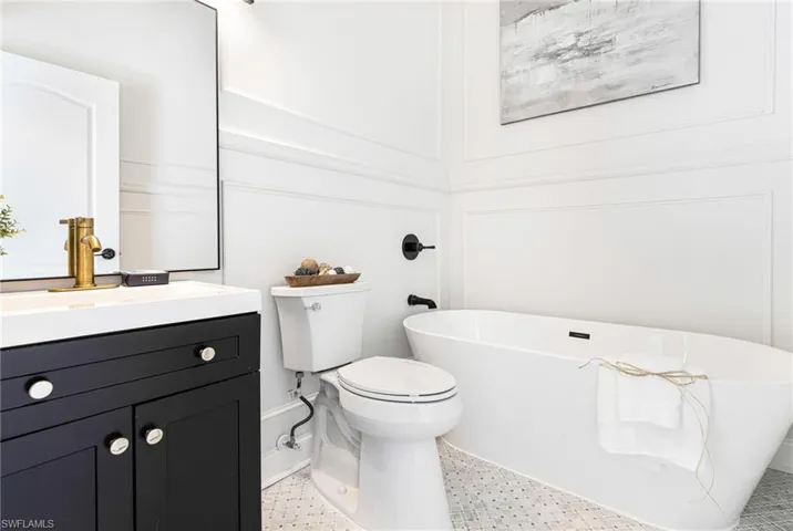 Bathroom featuring tile patterned floors, toilet, vanity, and a bathtub