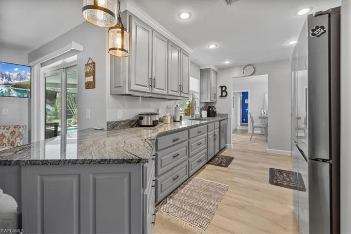 Kitchen featuring gray cabinetry, a sink, freestanding refrigerator, light wood-style flooring, and recessed lighting