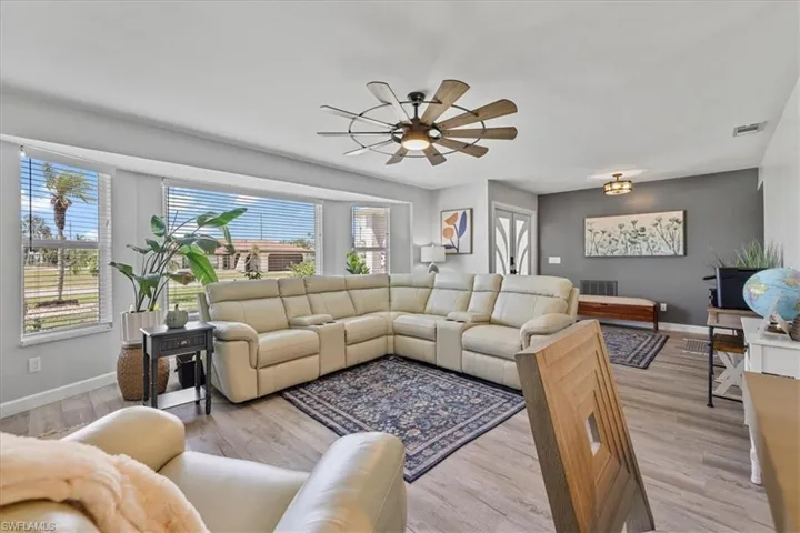 Living area with plenty of natural light, baseboards, a ceiling fan, and light wood-style floors