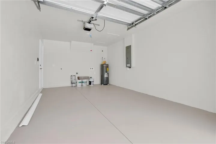 Garage with electric panel, water heater, and a garage door opener
