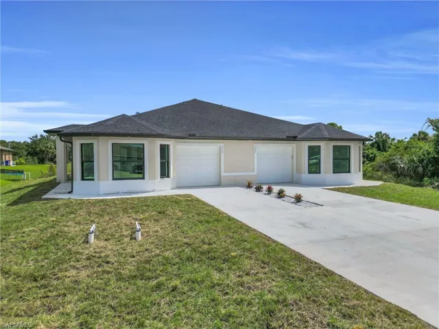View of front of home featuring stucco siding, driveway, and a front yard