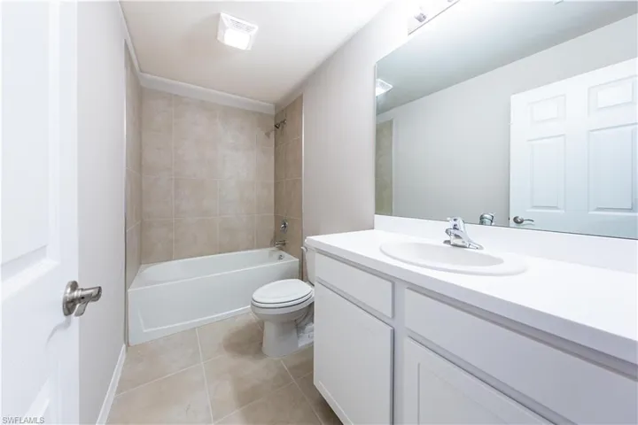 Bathroom with vanity, toilet, tile patterned flooring, and shower / bath combination