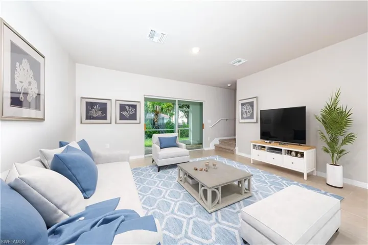 Tiled living area featuring baseboards and stairway