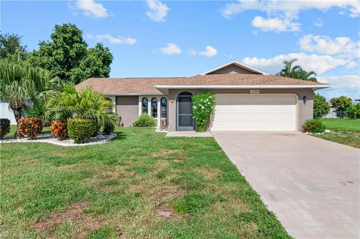 Ranch-style home featuring stucco siding, concrete driveway, an attached garage, and a front yard