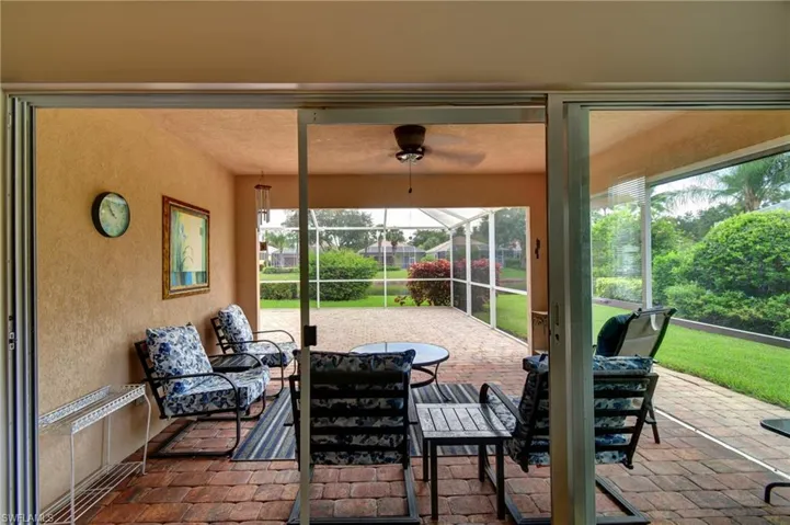 Screened-in patio with brick paver flooring, overhead ceiling fan, and sliding glass doors