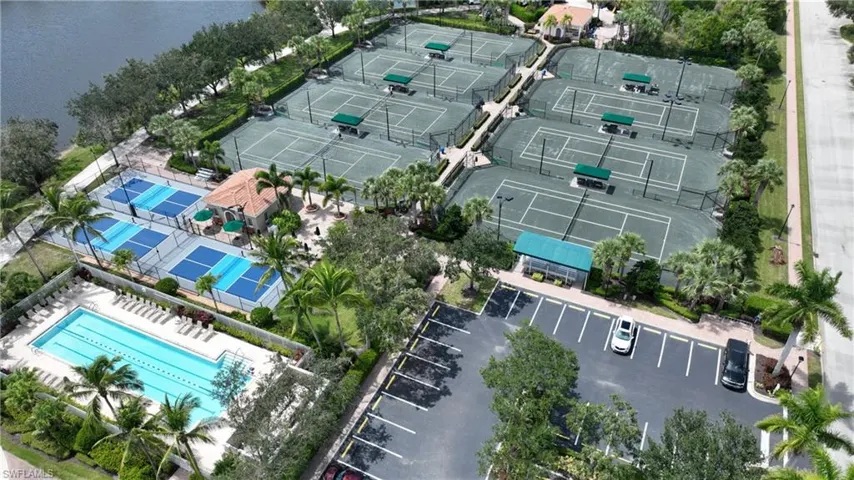 Extensive recreation area featuring multiple tennis courts, pickleball courts, an outdoor swimming pool with lap lanes, lush landscaping, and a dedicated parking lot