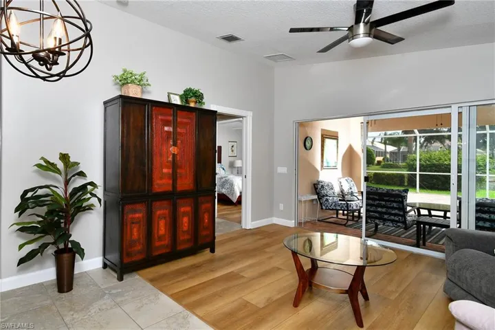Wood-finish flooring, vaulted ceiling, contemporary ceiling fan, and sliding glass door access to an outdoor screened area