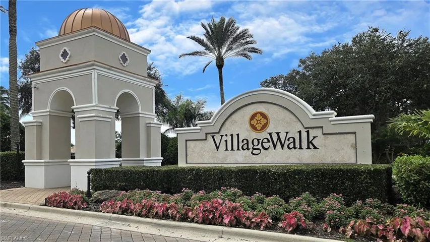 Arched entry structure with a domed copper roof, stone-finish signage, and landscaped grounds with mature foliage