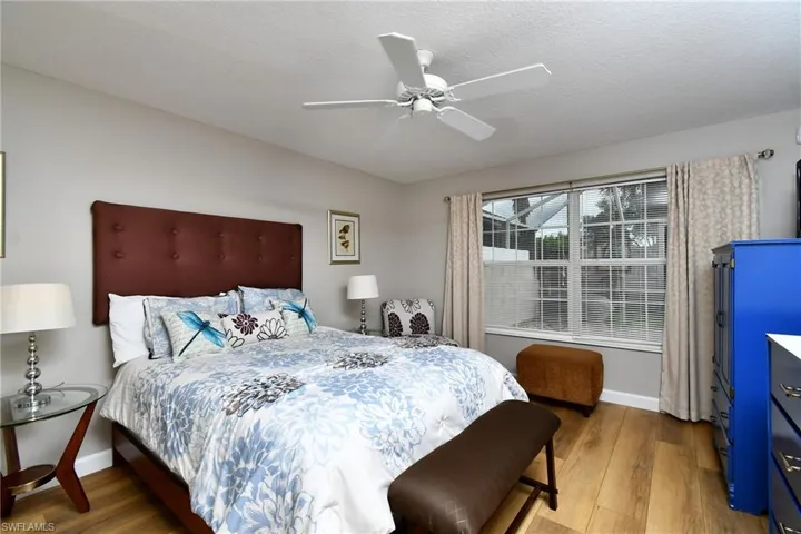 Wood-finish flooring, ceiling fan, and large window with vertical blinds