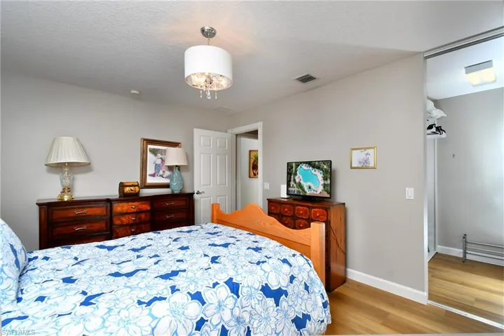 Wood-finish flooring, a contemporary drum shade chandelier, and a mirrored sliding closet door