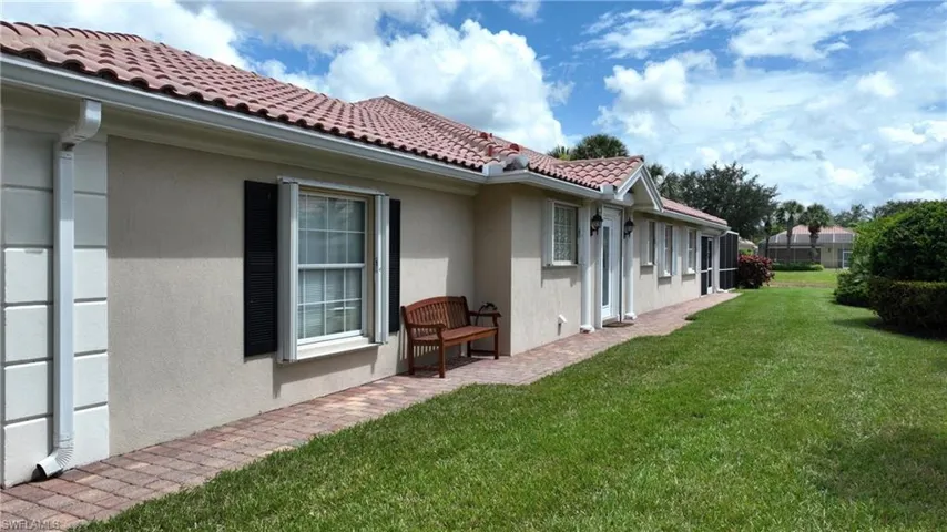 Stucco exterior with a tiled roof and white gutters
