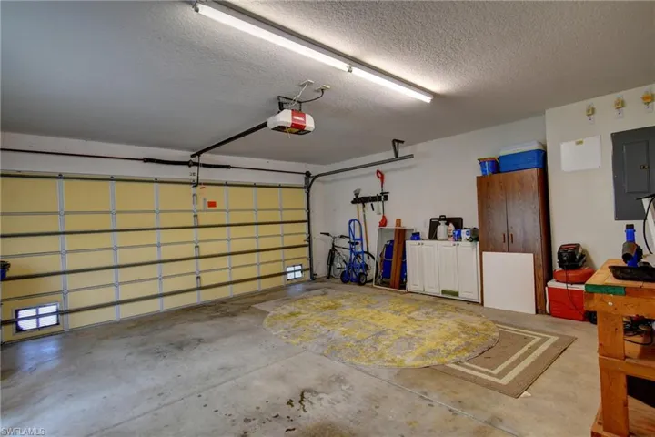 Spacious garage with concrete flooring, overhead lighting, and an automatic garage door opener