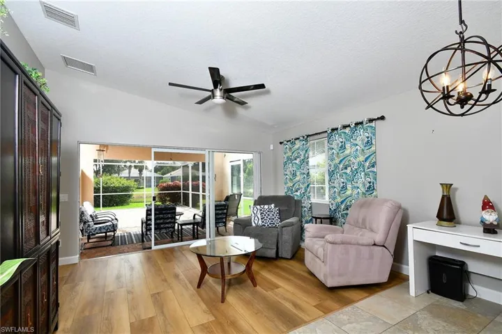 Vaulted ceiling with a ceiling fan, wood-finish flooring, and sliding glass doors opening to a screened patio