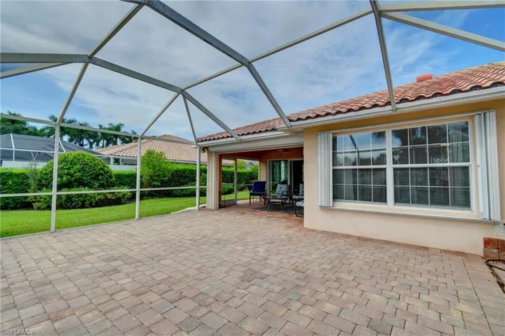 Screened outdoor living area featuring paver flooring, stucco exterior, and a tiled roof