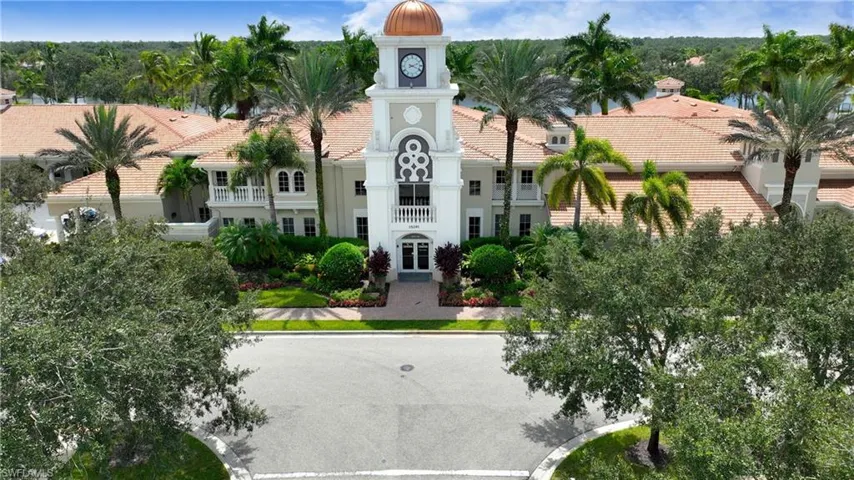 Elegant architectural design featuring a prominent clock tower with a dome, lush landscaping, mature palm trees, and terracotta-style tile roofing