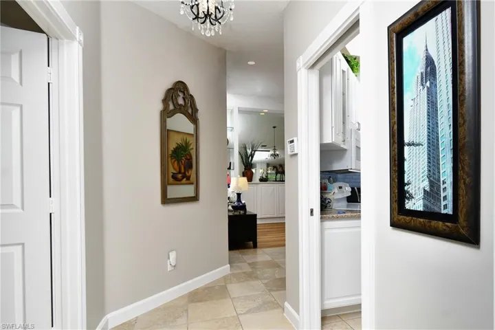 Hallway featuring tile flooring, a decorative chandelier, and light-colored walls