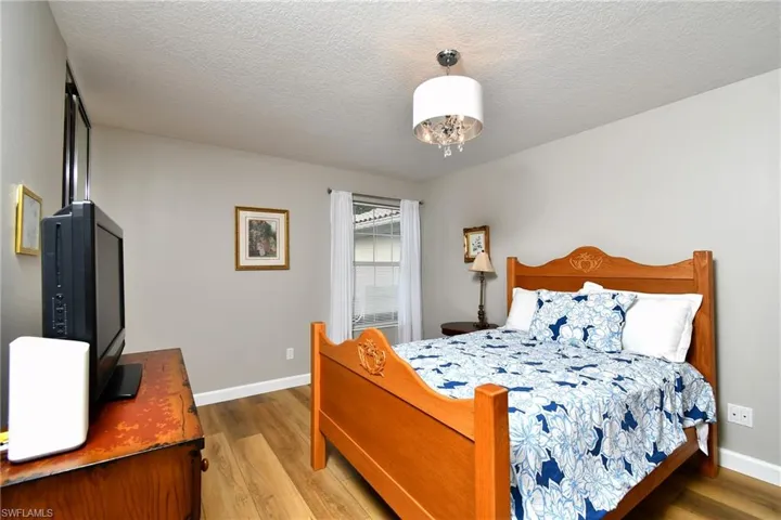 Wood-finish flooring, neutral wall tones, and a drum pendant light fixture with crystal accents