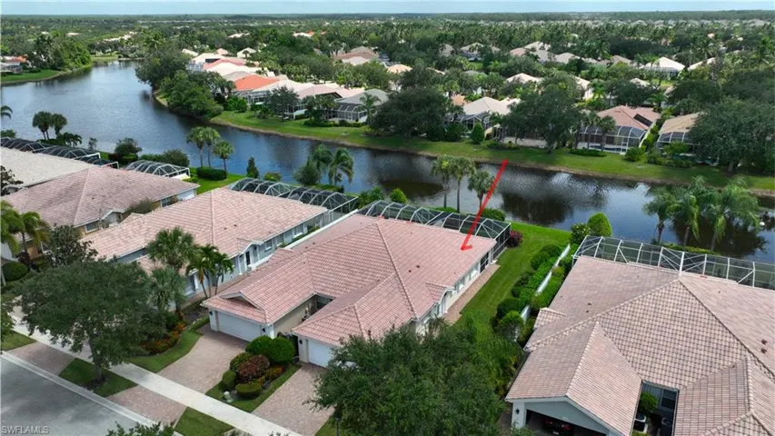 Waterfront property with a tile roof, screened lanai, landscaped yard, and a paver driveway