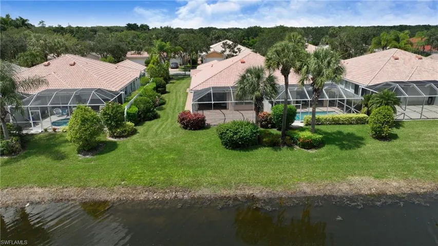 Screened-in pool area, mature landscaping, tiled roof, and waterside frontage