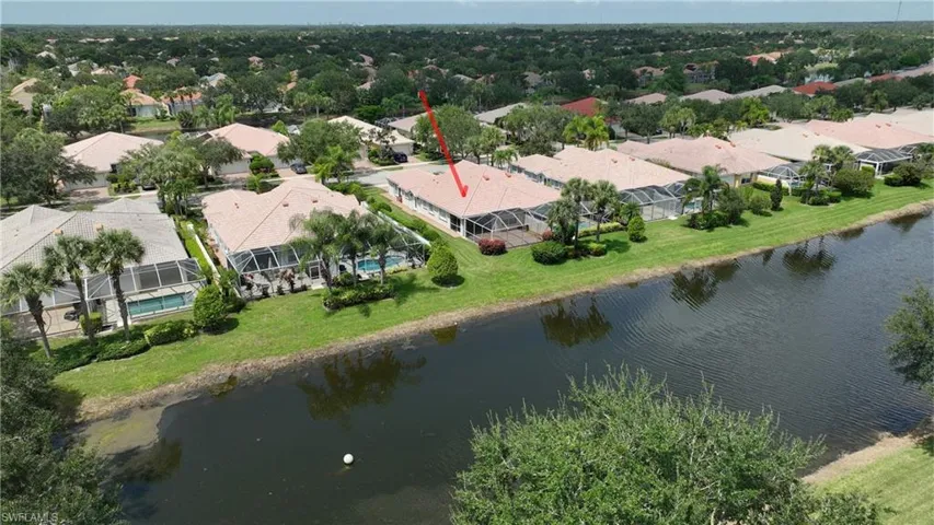Waterfront property featuring a screened-in lanai and mature landscaping