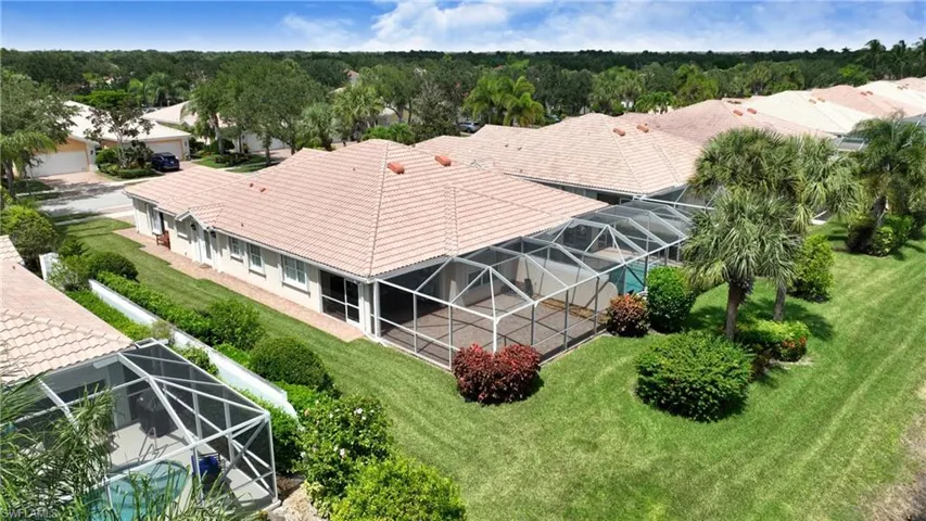 Property featuring a tile roof, screened enclosure, and established landscaping