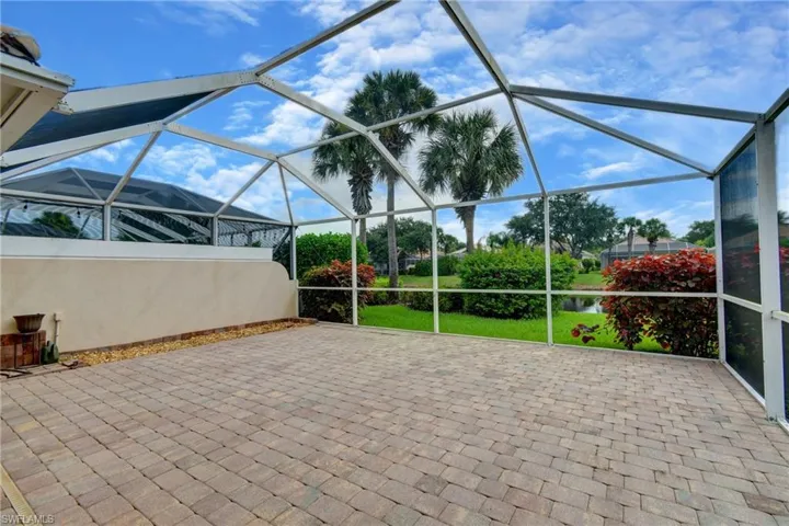 Screened lanai featuring paver flooring and a partial stucco privacy wall