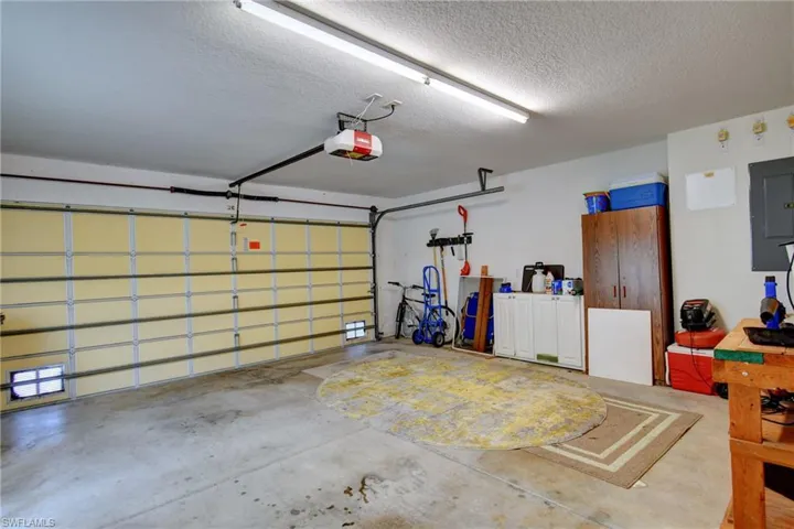 Garage space featuring a concrete floor, overhead fluorescent lighting, and a white paneled garage door with integrated windows