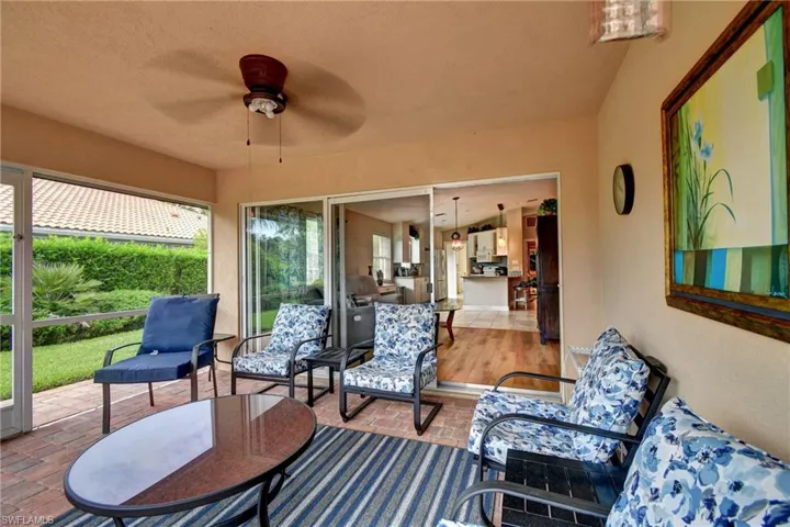Screened patio featuring a ceiling fan, brick-finish flooring, and sliding glass doors