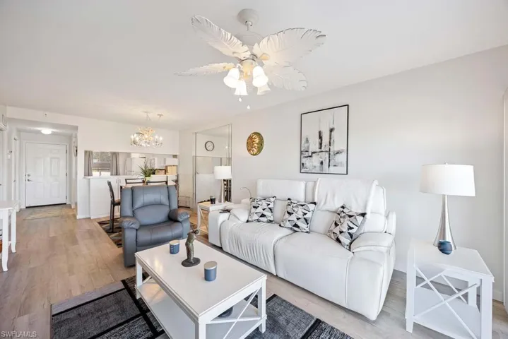 Living room with ceiling fan with notable chandelier and light hardwood / wood-style flooring