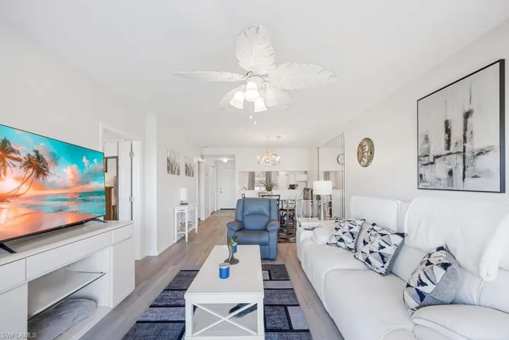 Living room featuring light wood-type flooring and ceiling fan with notable chandelier