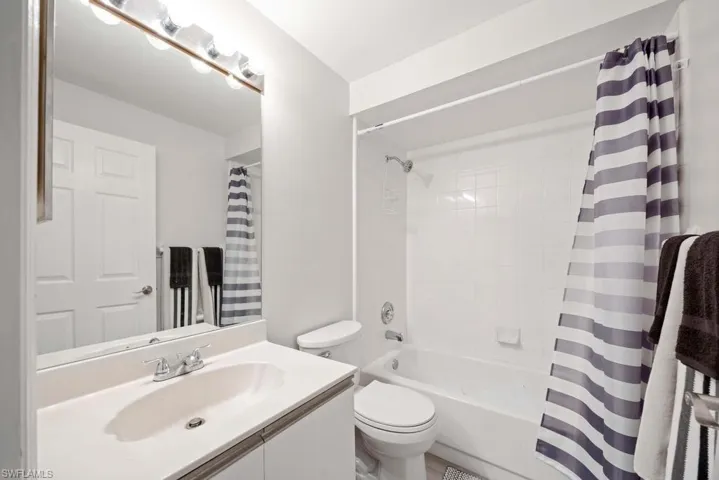 Full bathroom featuring toilet, shower / tub combo with curtain, and vanity