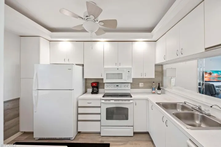 Kitchen with sink, white appliances, white cabinets, and crown molding